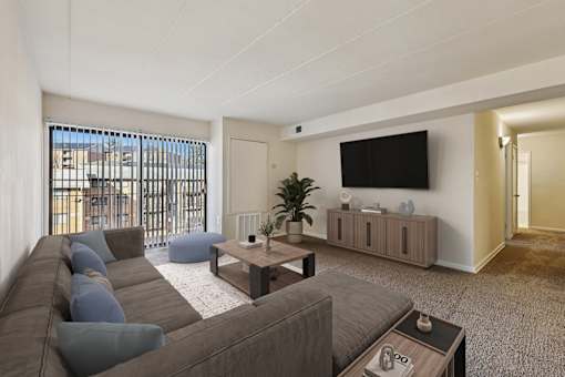 A living room with a grey couch and a flat screen TV mounted on the wall.