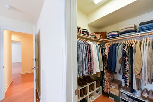 A walk in closet with clothes and shoes.