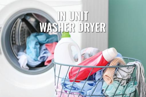 A laundry basket full of clothes is placed next to an open washer.