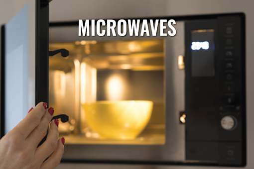 A person is holding a spoon in front of a microwave with a bowl inside.