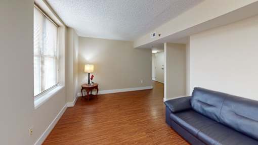 A living room with a blue couch and a small table with a vase of flowers on it.