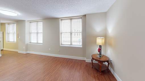 A room with a wooden floor and a table with a lamp on it.