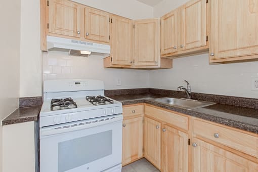kitchen with wood cabinetry, gas range and tile flooring at parkside apartments in washington dc
