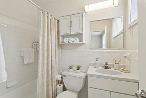 A white bathroom with a toilet, sink, and shower.