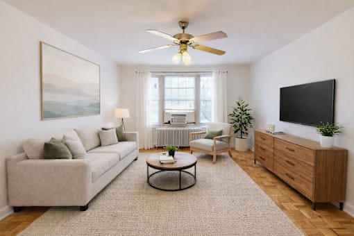 A living room with a beige couch, a coffee table, a ceiling fan, and a painting on the wall.