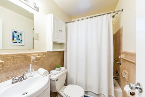 A bathroom with a white shower curtain and a white toilet.