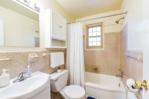 A white toilet sits in a bathroom with a white sink and a white bathtub.