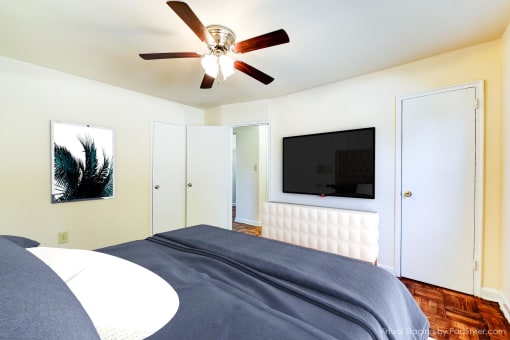 bedroom with bed, closet, dresser, wood floor and ceiling fan at the richman apartments in congress heights washington dc