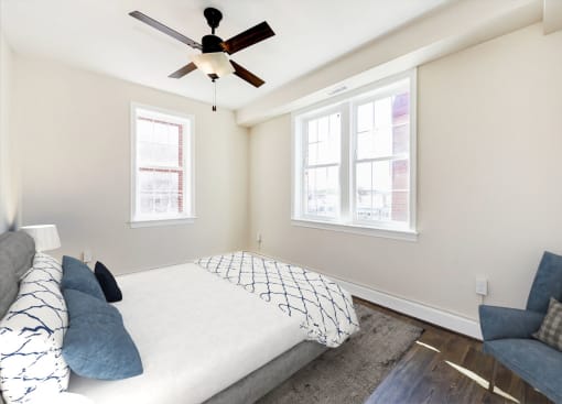 bedroom with bed, chair, large windows and ceiling fan at petworth station apartments in washington dc