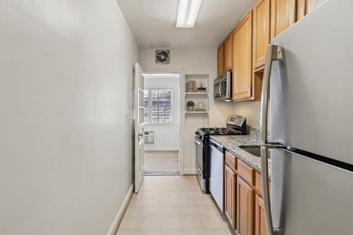 A kitchen with a white refrigerator, black dishwasher, and wooden cabinets.
