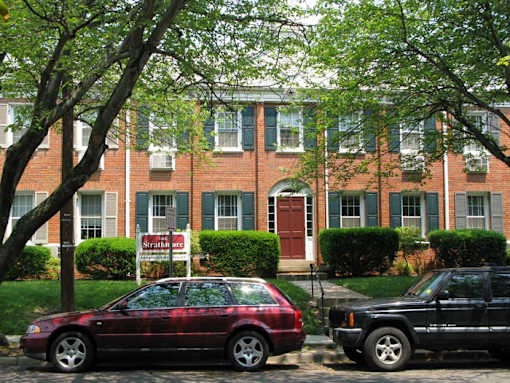 A red car is parked in front of a brick building.
