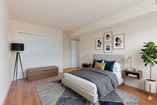 A bedroom with a large bed, a wooden bench, and a plant.