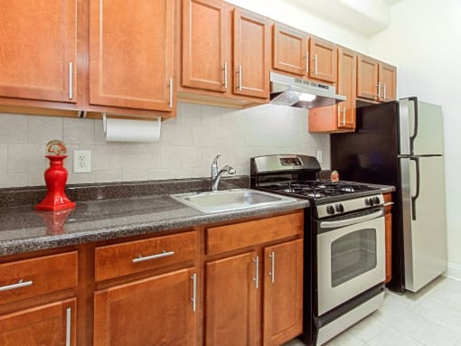 a kitchen with wooden cabinets and stainless steel appliances at the calverton apartment building in washington dc