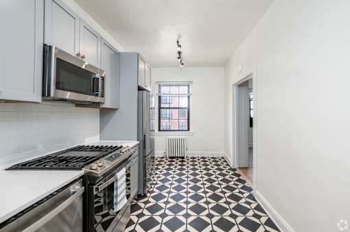A kitchen with black and white tiles on the floor.