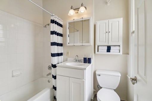 A white bathroom with a striped shower curtain.