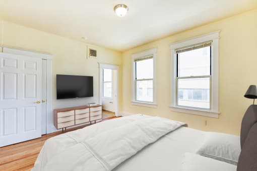 Bedroom with bed, dresser, tv, and large windows  at twin oaks apartments columbia heights washington dc