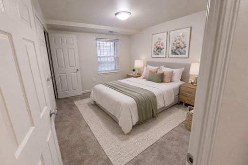 A bedroom with a bed, nightstand, and two pictures on the wall.