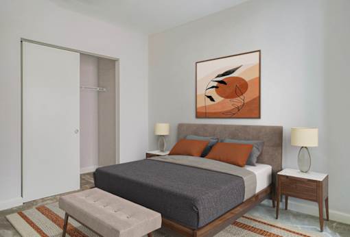 A bedroom with a bed, nightstands, and a painting on the wall.at 405 W Redwood Apartments, Maryland, 21201