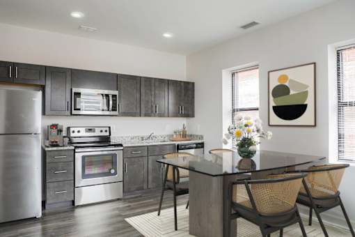 A modern kitchen with a stainless steel refrigerator, a microwave, and a stove top oven.at 405 W Redwood Apartments, Baltimore, MD 21201  