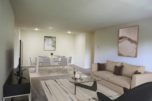 A living room with a couch, a dining table, and a television.