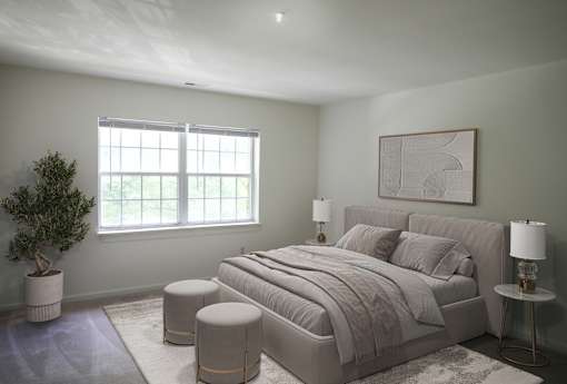 A bedroom with a large bed, a potted plant, and a framed artwork on the wall.