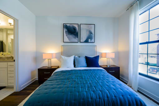 a bedroom with a blue comforter on a bed and two windows at Ingram Manor, Pikesville, MD