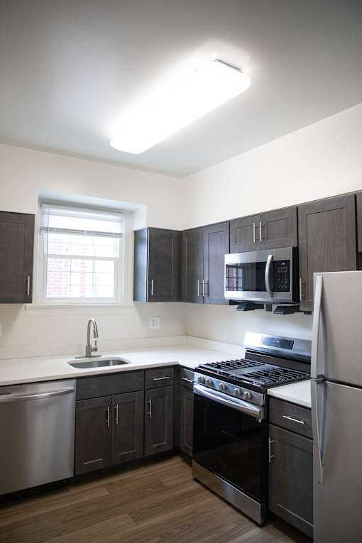 A kitchen with a stove, sink, and refrigerator.