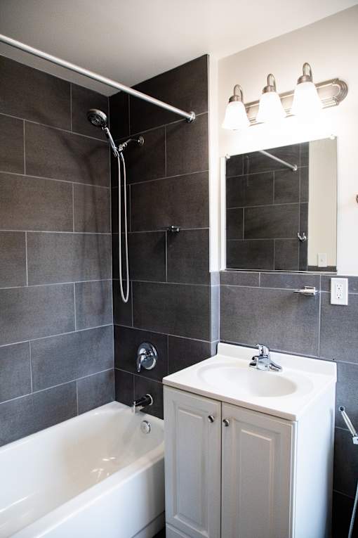 A white bathroom sink with a white tub and a white cabinet.