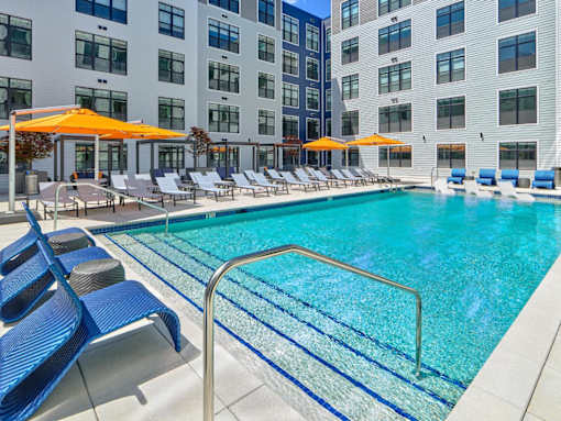 A swimming pool with outdoor seating at The Apartments at Metro Centre