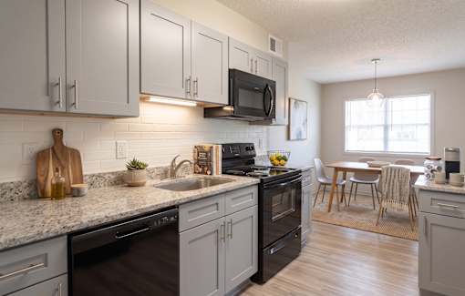 A kitchen with a black oven and a black microwave above the stove.