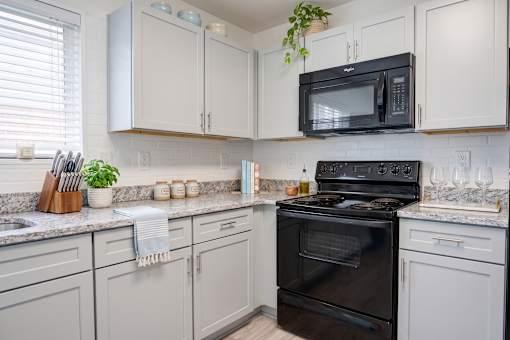 A kitchen with a black stove and white cabinets.