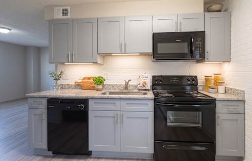 A modern kitchen with a black stove and white cabinets.