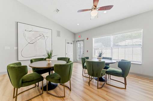 A room with a table and chairs and a ceiling fan.