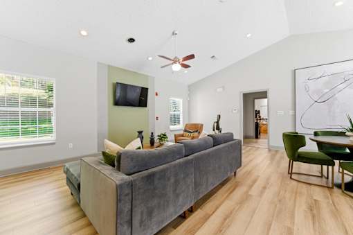 A living room with a grey couch and a television on the wall.
