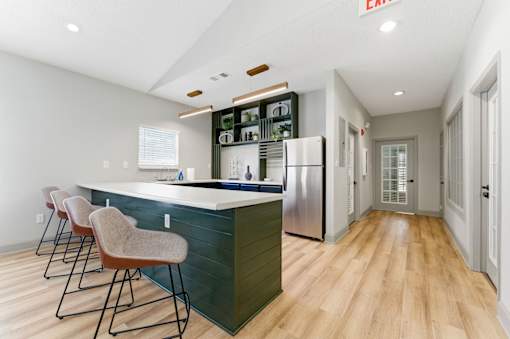 A kitchen with a bar area and chairs.