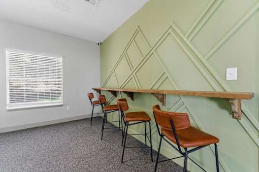 A room with green walls and a wooden shelf with chairs.
