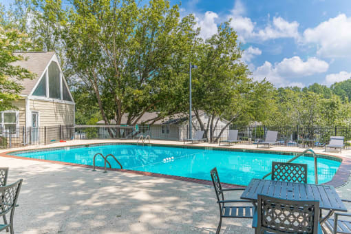a swimming pool with a table and chairs and a house in the background at Bradford Gwinnett Apartments, Georgia , 30071
