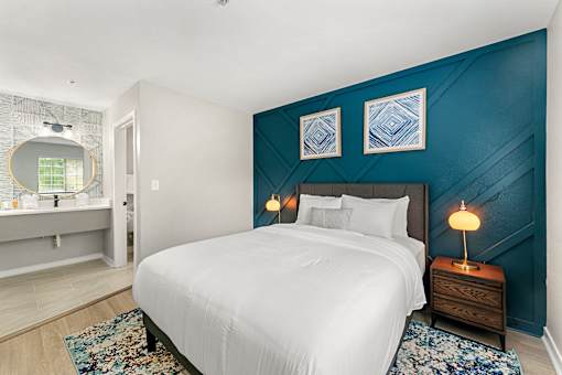 A bedroom with a white bed and a blue accent wall.