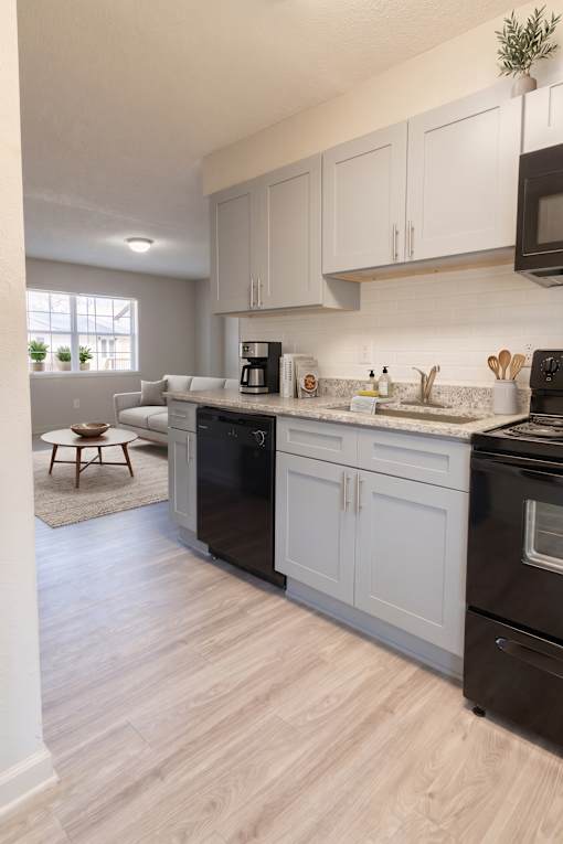 A kitchen with black appliances and white cabinets.