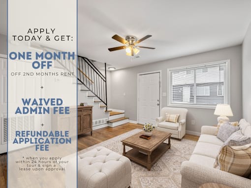 A room with a staircase and a couch with a sign offering a free month of rent.