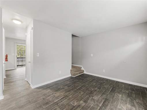 Room with wooden floor and carpeted staircase at Pinewood Townhomes, Tucker, 30084