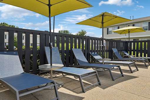 A row of sun loungers are on a patio.