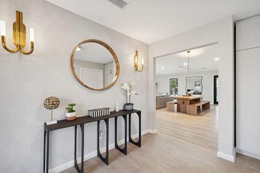 A modern hallway with a round mirror and two wall sconces.