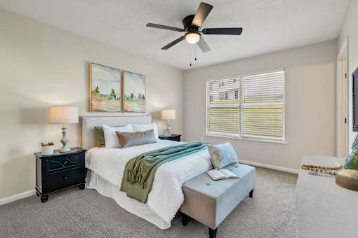 A bedroom with a bed, nightstand, and window with blinds.