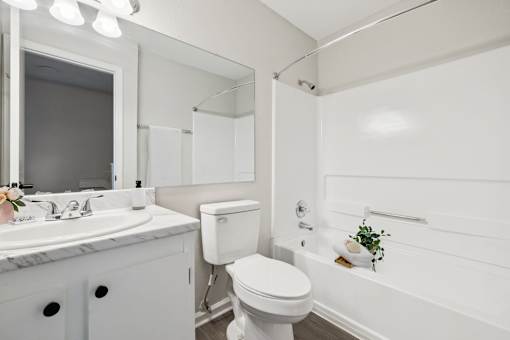 A white bathroom with a toilet, sink, and bathtub.