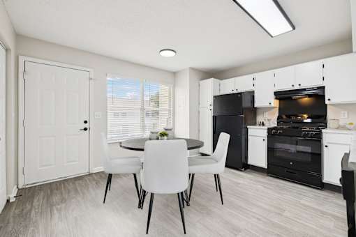 A kitchen with a table and chairs in front of a white door.