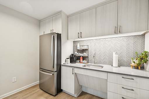 A kitchen with a refrigerator, sink, and cabinets.