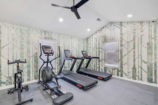 A home gym with a treadmill, elliptical trainer, and stationary bike.