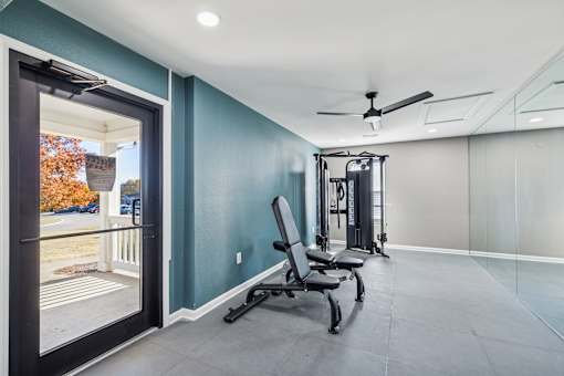 A room with a treadmill, exercise bike, and weights.
