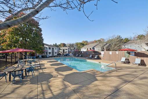 A pool surrounded by chairs and umbrellas.